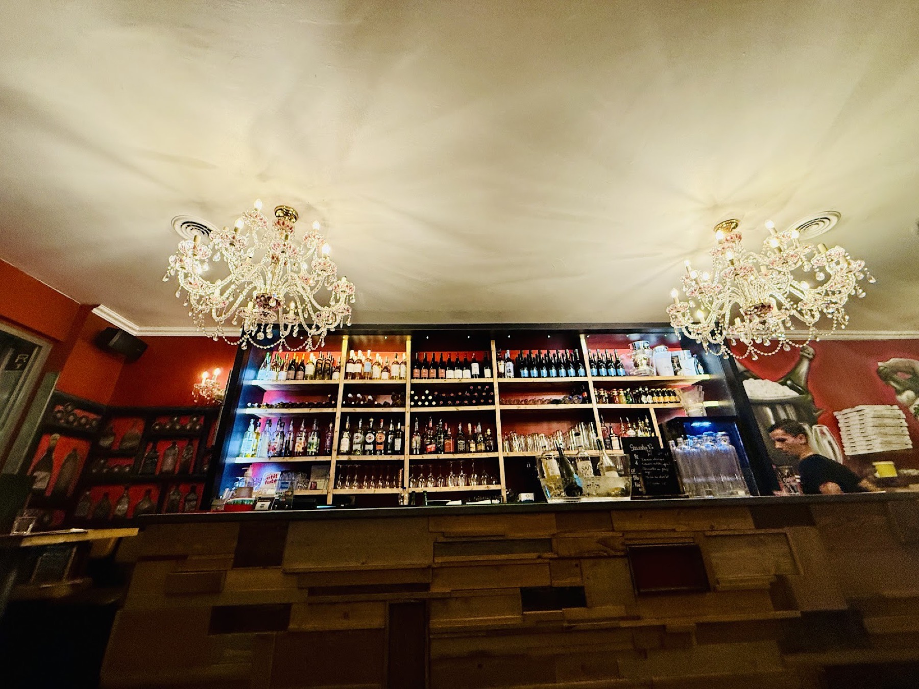 Le bar et ses bouteilles alignées, sous les deux lustres de Murano en cristal