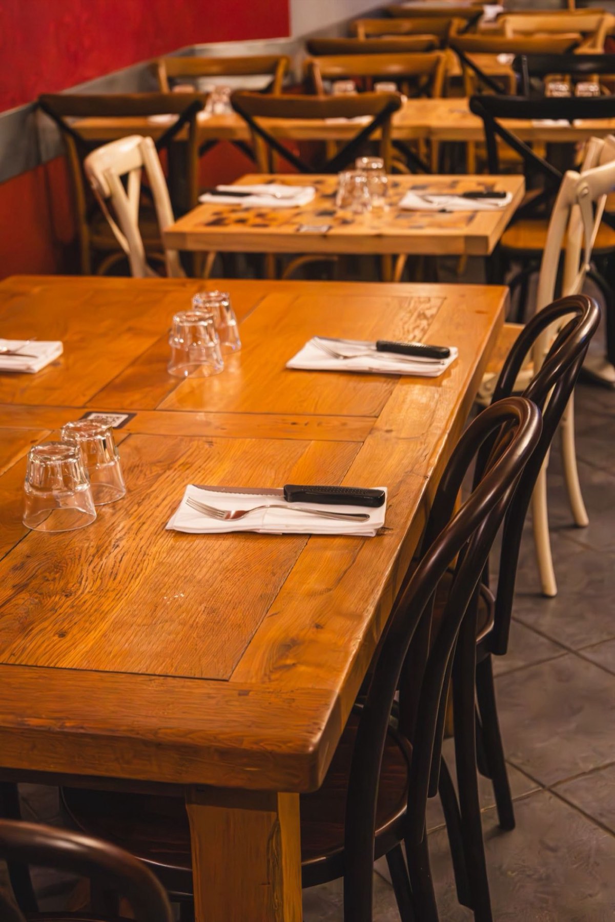 La salle et ses tables en bois massif, dressées pour le service
