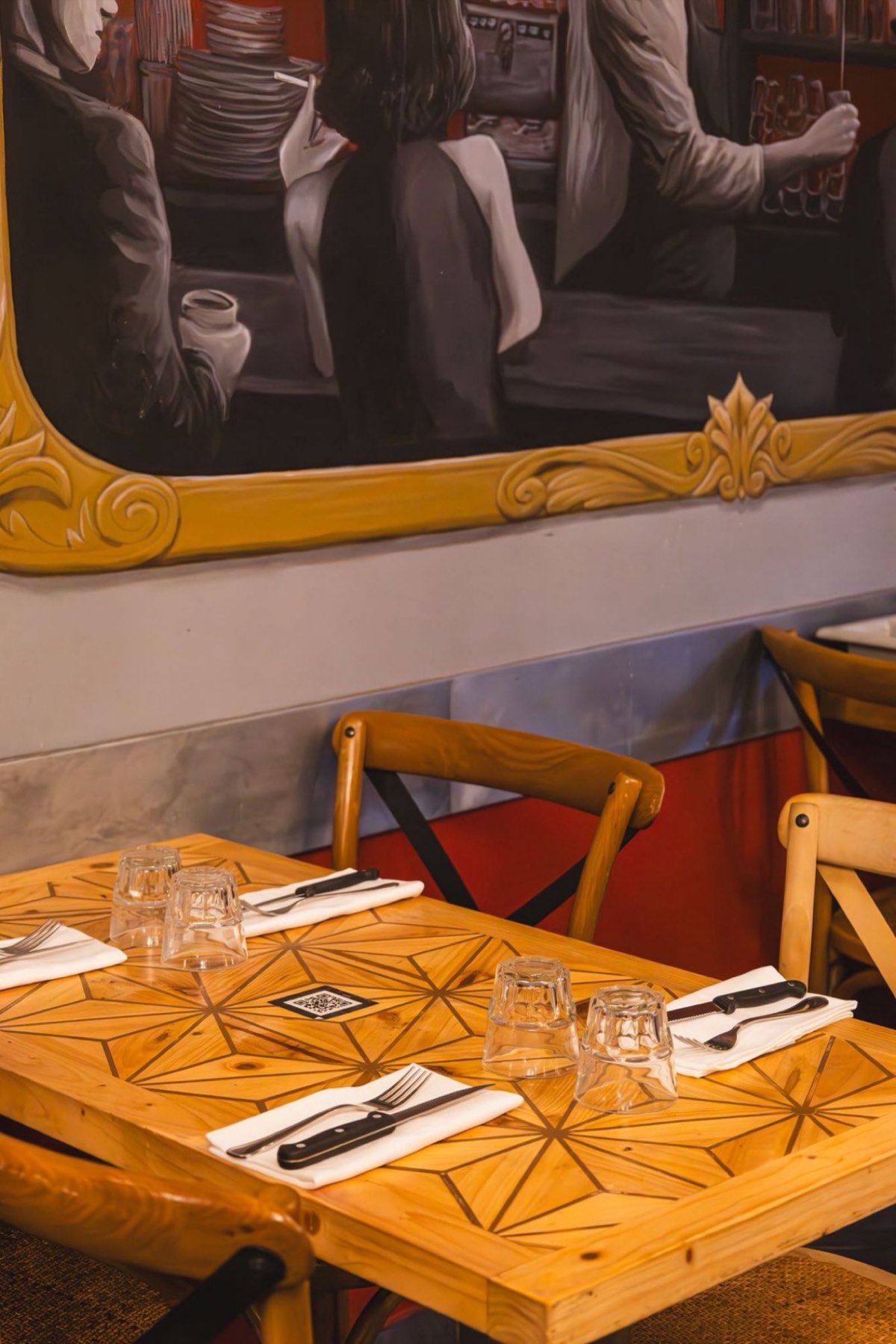 La fresque du bar dans son cadre doré peint, au-dessus des tables marquetées