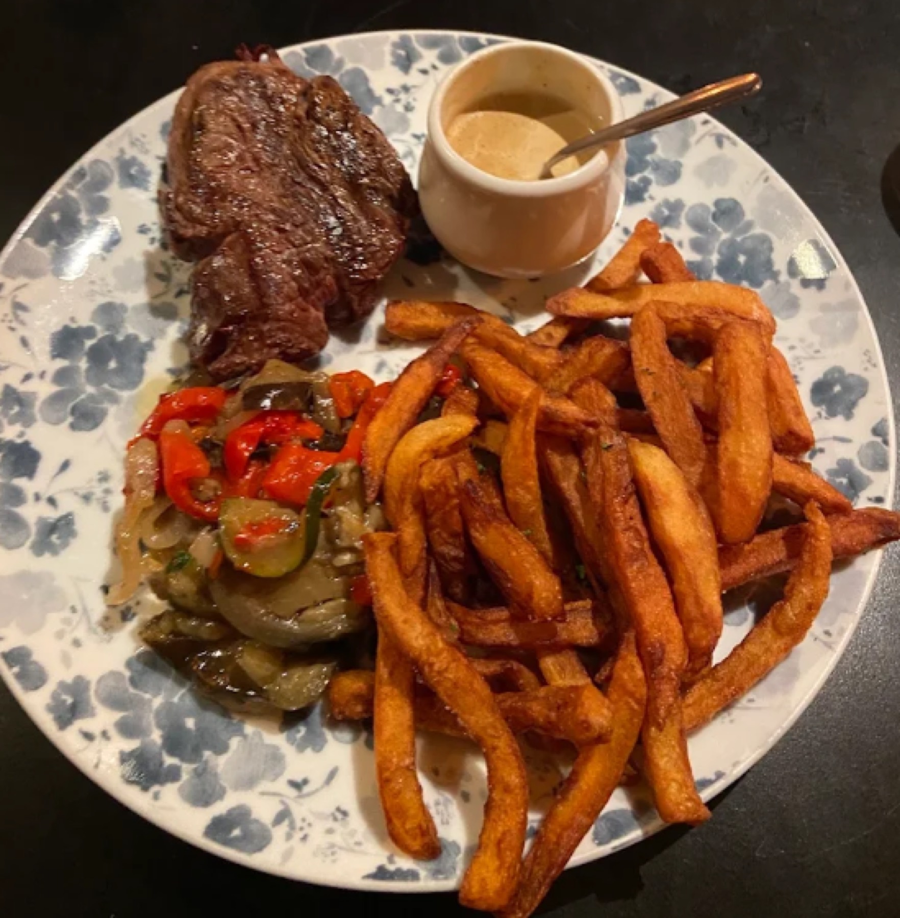 Une entrecôte grillée, des frites maison et des poivrons, la sauce servie à part